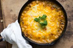 a skillet filled with food sitting on top of a wooden table next to a white towel