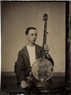 an old black and white photo of a man holding a small instrument in his right hand