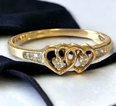 two heart shaped diamond ring sitting on top of a black ribbon