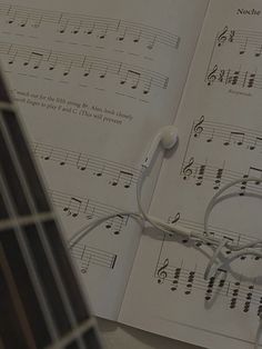 an open book with musical notes and headphones laying on top of it next to a guitar