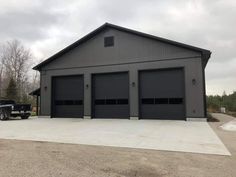 a truck parked in front of a large gray building with two garages on each side