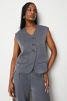 Tailored boxy silhouette for a modern, structured look Sleeveless design with deep V-neckline Button-front closure with chic metallic buttons Welt pocket detailing at chest Straight hem for a clean finish Exuding confidence and sophistication, this tailored waistcoat effortlessly elevates any smart ensemble. Style it with a crisp shirt and tailored trousers for the office, or pair with a slinky dress for an evening soirée. The boxy fit and sleeveless cut create a contemporary, flattering silhouette that epitomises the brand's edgy yet feminine aesthetic. Whether dressing for a corporate meeting or a special occasion, this versatile piece adds a touch of refined polish. Short Holiday Dresses, Tailored Waistcoat, Corporate Meeting, Slinky Dress, Oasis Fashion, Summer Linen, Tshirt Skirt, Feminine Aesthetic, Tailored Trousers