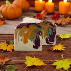 two soap bars sitting on top of a wooden table surrounded by fall leaves and candles