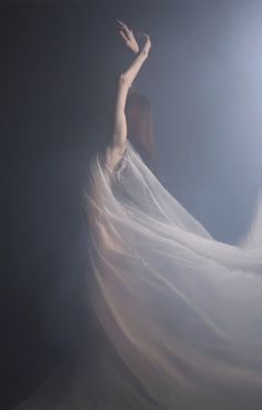 a woman in a white dress with her arms outstretched