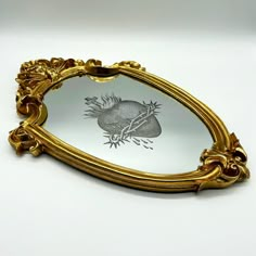 an ornate gold framed mirror with a drawing of a fish on it's side