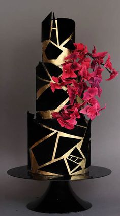 a black and gold cake with pink flowers on top