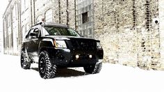 a black hummer truck parked in front of a brick building on a snowy day