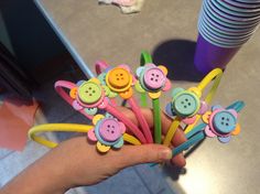 a person holding a bunch of colorful hair clips with buttons on them and flowers in the middle