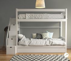 a white bunk bed sitting on top of a hard wood floor next to a rug