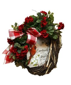 a wreath with red flowers and a card in the middle is hanging on a wall