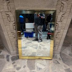 a man standing in front of a mirror with his reflection on the wall behind him