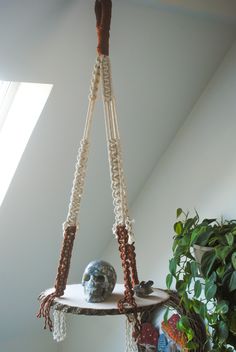 a hanging shelf with beads, chains and a skull in the corner next to a potted plant