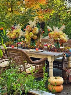 an outdoor dining area with wicker furniture and pumpkins on the table, surrounded by greenery