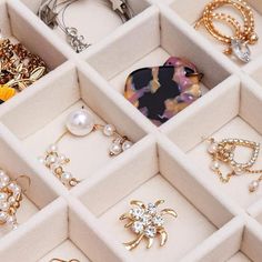 an assortment of jewelry is displayed in a white box with gold chains, earrings and brooches