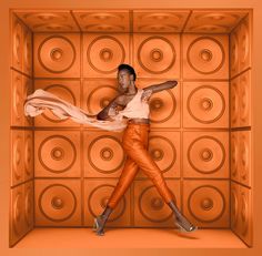 a woman standing in front of an orange wall