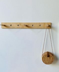 a wooden wall hanging with two hooks and a basket