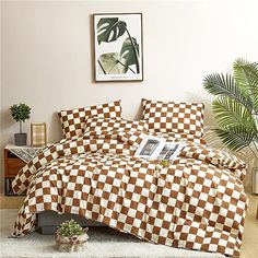 a bed covered with checkered sheets and pillows in a room next to a potted plant