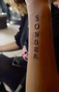 someone with a tattoo that says sonder on their arm and the word sonder written in cursive font