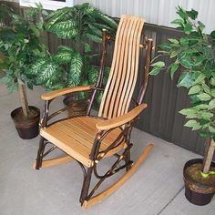 a wooden rocking chair sitting next to a potted plant