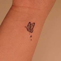 a small butterfly tattoo on the wrist is shown in black and grey ink with stars around it