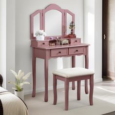 a pink vanity table with mirror and stool