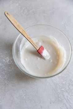 a glass bowl filled with yogurt and a wooden stick sticking out of it