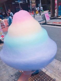 an ice cream cone sitting on top of a sidewalk next to a street with people in the background