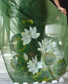 a woman is walking down the street wearing a green dress with white flowers on it