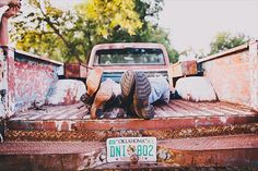 a person laying on the back of an old pick up truck with their feet in the bed