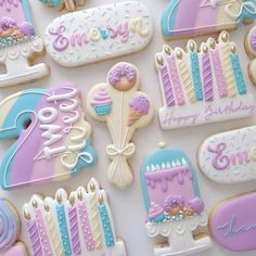 decorated birthday cookies are displayed on a white tablecloth with blue, pink and purple icing