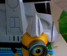 a yellow and black minion toy sitting on top of a desk next to a computer