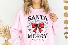 a woman wearing a pink santa and co merry christmas sweatshirt with red bow on the front