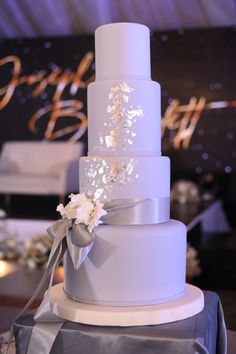 a white wedding cake with silver ribbon and flowers