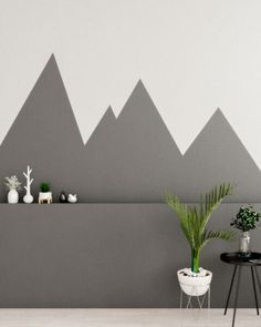 a living room with mountains painted on the wall and potted plants next to it