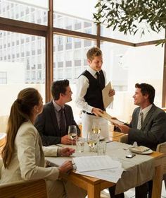 a group of people sitting around a table with papers and wine glasses in front of them