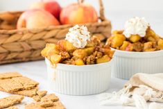 two white bowls filled with dessert next to some crackers and apples in the background