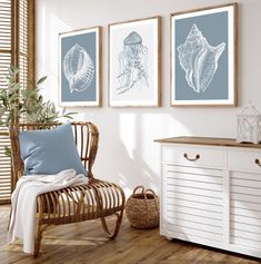 three framed pictures hang on the wall next to a wicker chair and sideboard