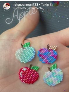 three small pieces of beaded fruit on a person's hand with the words, apple