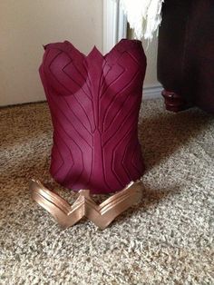 a pair of gold shoes sitting on top of a floor next to a red vase