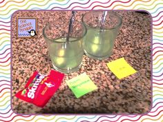 two glasses filled with green liquid sitting on top of a counter next to candy bars