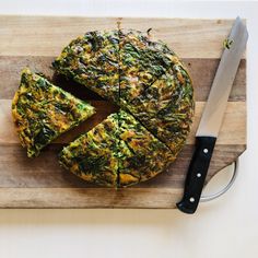 a cheesecake with spinach on a cutting board next to a knife