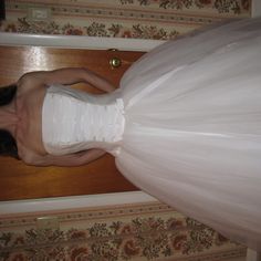 a woman in a wedding dress is standing on the door way with her hands behind her back