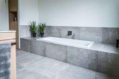 a bath tub sitting next to a plant in a bathroom