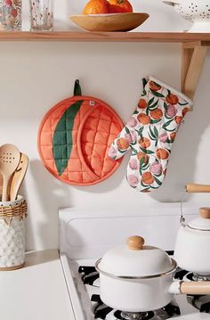 an oven mitt hanging on the wall next to pots and pans with wooden spoons