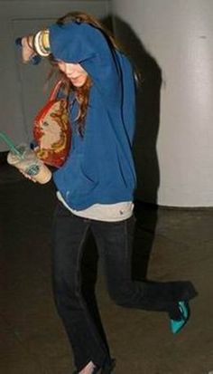 a woman is skateboarding in an empty room with her hand on her hip and one foot off the ground