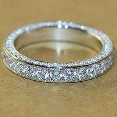 a wedding ring with three rows of diamonds on it's sides, sitting on a table