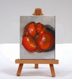 an easel with a painting of tomatoes on it