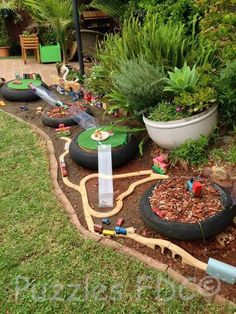 an outdoor play area with lots of toys in the grass and plants growing on the ground