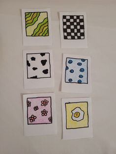 four squares with different designs on them sitting on a white tablecloth covered surface in front of a wall