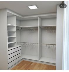 an empty walk in closet with lots of white shelves and glasses hanging on the hooks